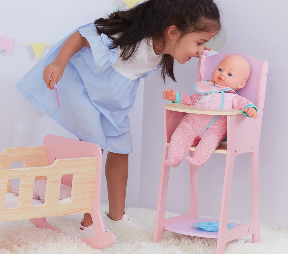 Girl feeding a baby doll in an Olivia's Little World high chair