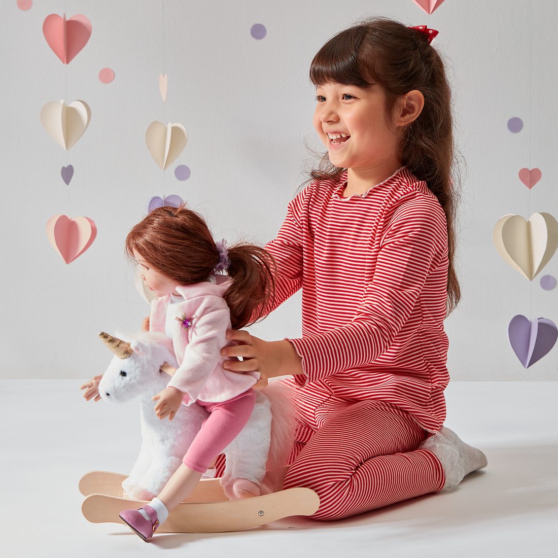 Girl with her doll on an Olivia's Little World rocking horse